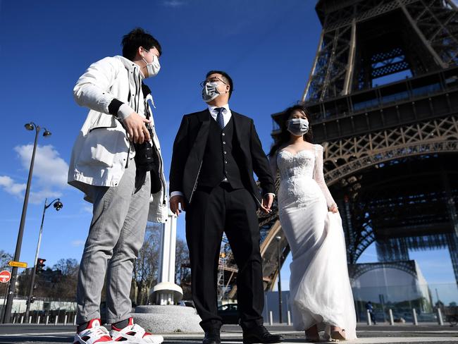 Newlyweds wearing face masks take photos in front of the Eiffel Tower in Paris. Picture: AFP