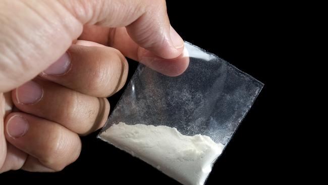 Generic photo of cocaine. Dealer is holding drug bag in his hand on a black background. Picture: iStock