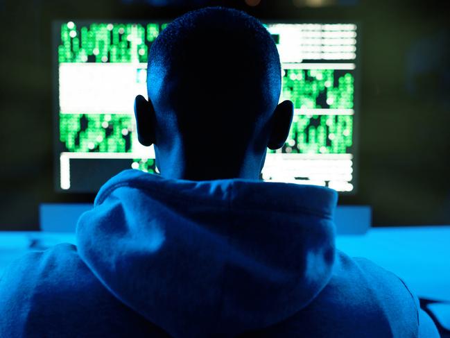 Rearview shot of a male hacker cracking a computer code in the dark