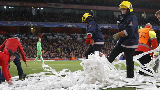 Ground staff and fire fighters clear toilet rolls that were thrown onto the pitch.
