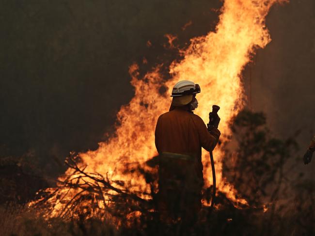 Tasmania Fire Service personnel put out a spot fire threatening a home on Donnelleys Road, Geeveston. Picture: LUKE BOWDEN