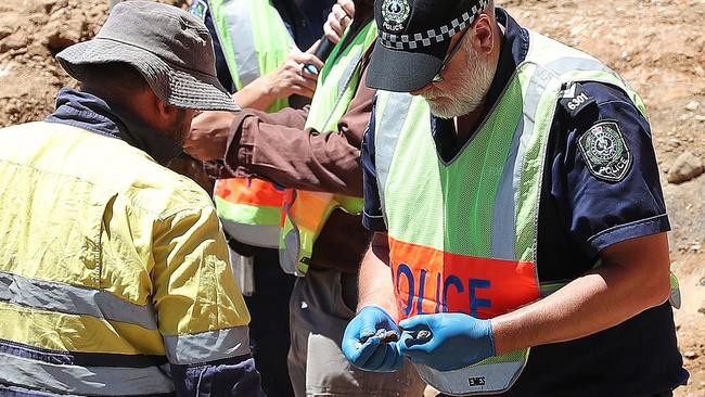 A forensic crime scene investigator looking at items found in the soil. Picture: Dylan Coker