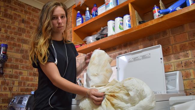 MUDDY: Clermont Country Motor Inn housekeeper Jess Walsh shows what the discoloured water in Clermont had done to the motel's laundry. Photo: Zizi Averill