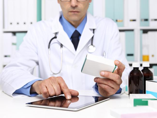 Doctor reading a Digital Tablet with drug boxes in hand  at Office Desktop. Health care, Medical and Pharmacy Concept.