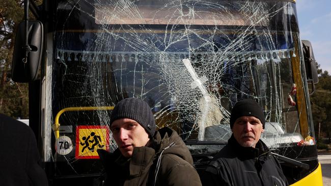 Yuri (R), a bus driver, and his son Ruslan, a doctor, stand in front of a bus damaged in this morning’s air strikes at a nearby military complex. Picture: Dan Kitwood/Getty Images