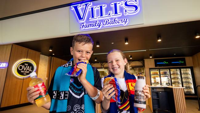 Young footy fans testing out some of the new food and drink items at a kiosk at Adelaide Oval, including the new $5 Vili’s pies and sausage rolls. Picture: James Elsby