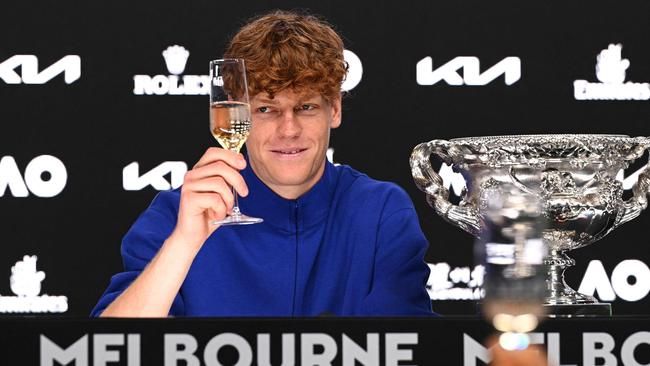 Jannik Sinner raises his glass to toast his victory during a press conference after winning the 2025 Australian Open final. Photo by Vince CALIGIURI / TENNIS AUSTRALIA / AFP.