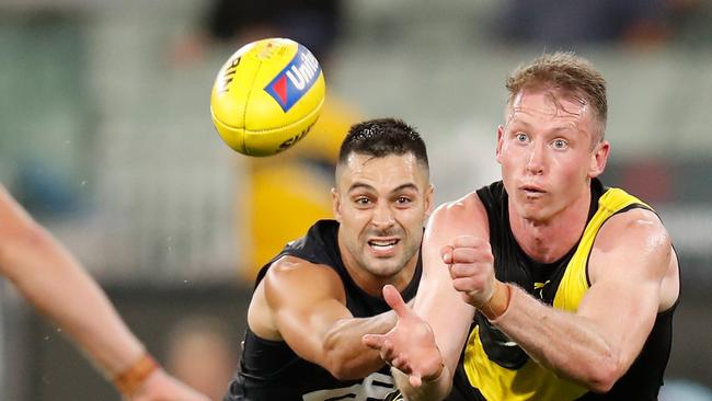 MELBOURNE, AUSTRALIA – MARCH 18: Dylan Grimes of the Tigers handpasses the ball against Michael Gibbons of the Blues during the 2021 AFL Round 01 match between the Richmond Tigers and the Carlton Blues at the Melbourne Cricket Ground on March 18, 2021 in Melbourne, Australia. (Photo by Michael Willson/AFL Photos via Getty Images)