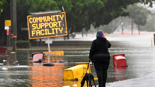 LISMORE, AUSTRALIA - MARCH 30: A woman walks her dog on a flooded road on March 30, 2022 in Lismore, Australia. Evacuation orders have been issued for towns across the NSW Northern Rivers region, with flash flooding expected as heavy rainfall continues. It is the second major flood event for the region this month. (Photo by Dan Peled/Getty Images)