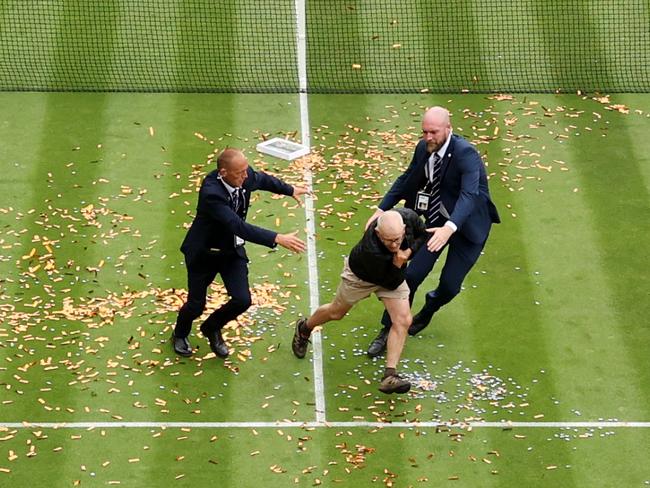 LONDON, ENGLAND - JULY 05: A protester is challenged by security on court 18 after a Just Stop Oil protest using orange confetti and a jigsaw puzzle during the Women's Singles first round match between Katie Boulter of Great Britain and Daria Saville of Australia during day three of The Championships Wimbledon 2023 at All England Lawn Tennis and Croquet Club on July 05, 2023 in London, England. (Photo by Julian Finney/Getty Images)