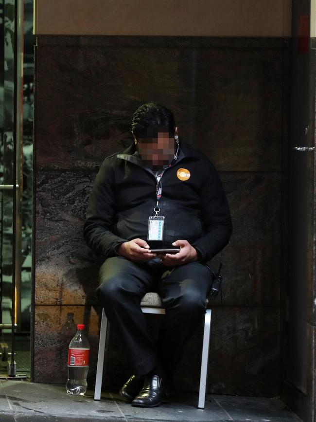 A Unified Security guard whiles away the hours while on duty. Picture: Jonathan Ng