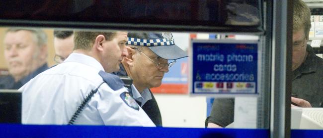 Then-Constable Troy Amos and former Sergeant Ian Reimers view CCTV as police investigate an armed robbery at Freedom Fuels service station on corner of Taylor and Greenwattle Streets where the offender used a broken bottle as a weapon on June 28, 2008.