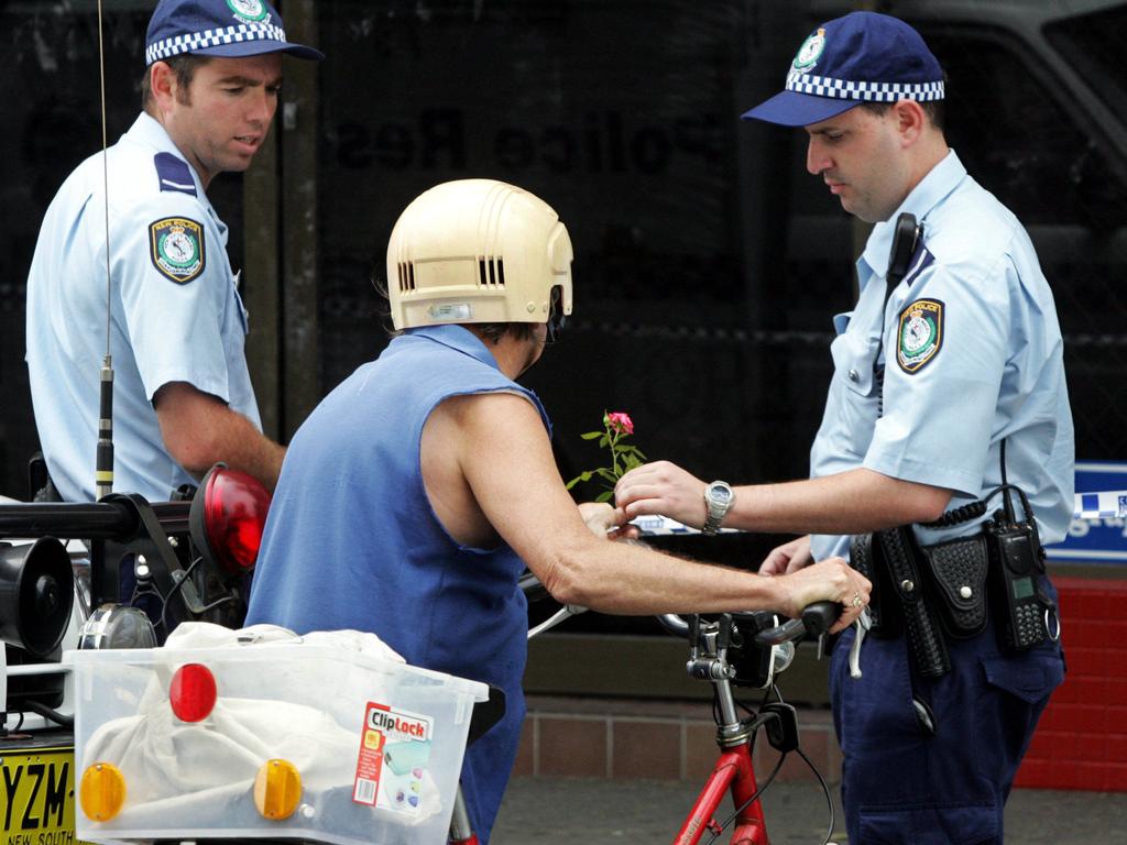 A woman hands a rose to a police officer at the scene of the murder of store owner Frank Newbery.