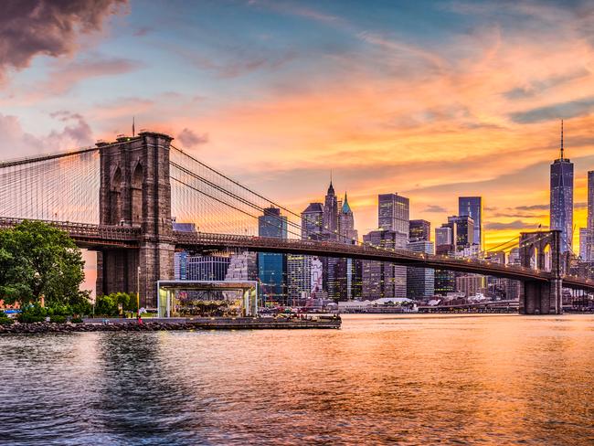 New York City Skyline on the East River with Brooklyn Bridge at sunset.