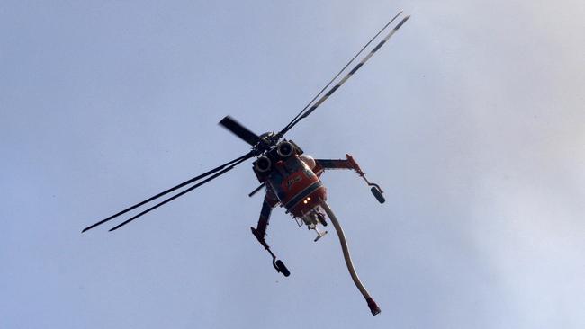 A fire bombing helicopter in the sky's above Lemon Tree Passage Rd, Salt Ash on Friday morning. Picture: AAP