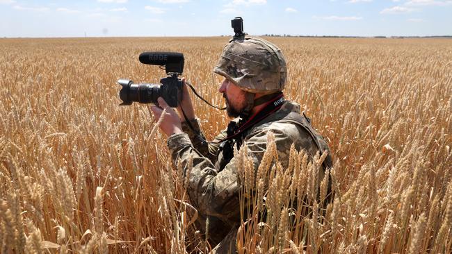 A Ukrainian military journalist takes cover in a wheat field in the Donetsk district at the weekend. Picture: Getty Images