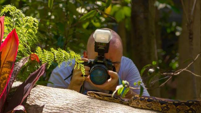Todd Michaelsen behind the lense photographing a python. Photo: Todd Michaelsen/@todds_wildlife