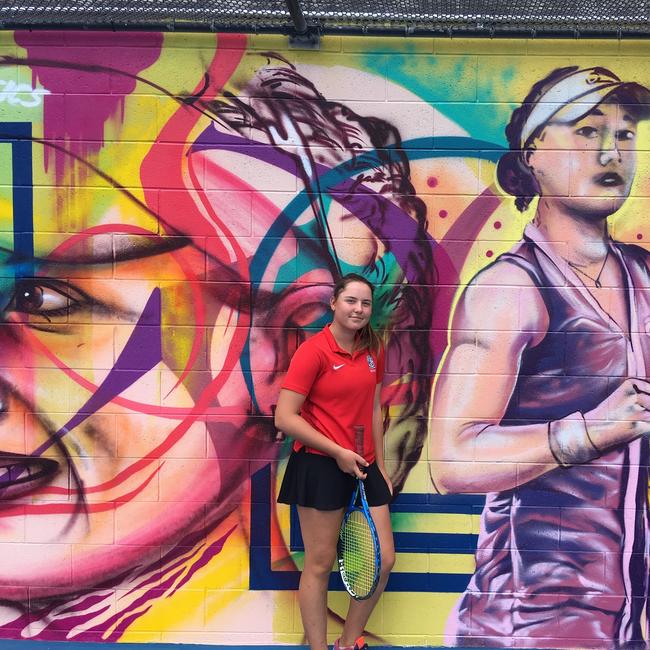 Kelvin Grove State High School tennis players Sydney Stone in front of the Ashleigh Barty mural at the Queensland Tennis Centre.