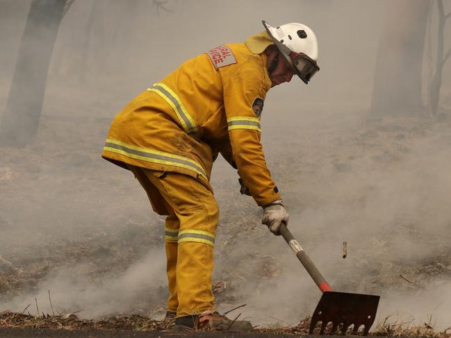 A firefighter uses a rake to battle a fire near Burrill Lake, Sunday, Jan. 5, 2020. Milder temperatures Sunday brought hope of a respite from wildfires that have ravaged three Australian states, destroying almost 2,000 homes. (AP Photo/Rick Rycroft)