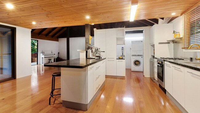 The kitchen features gas cooking, stone benchtops and brass hardware.