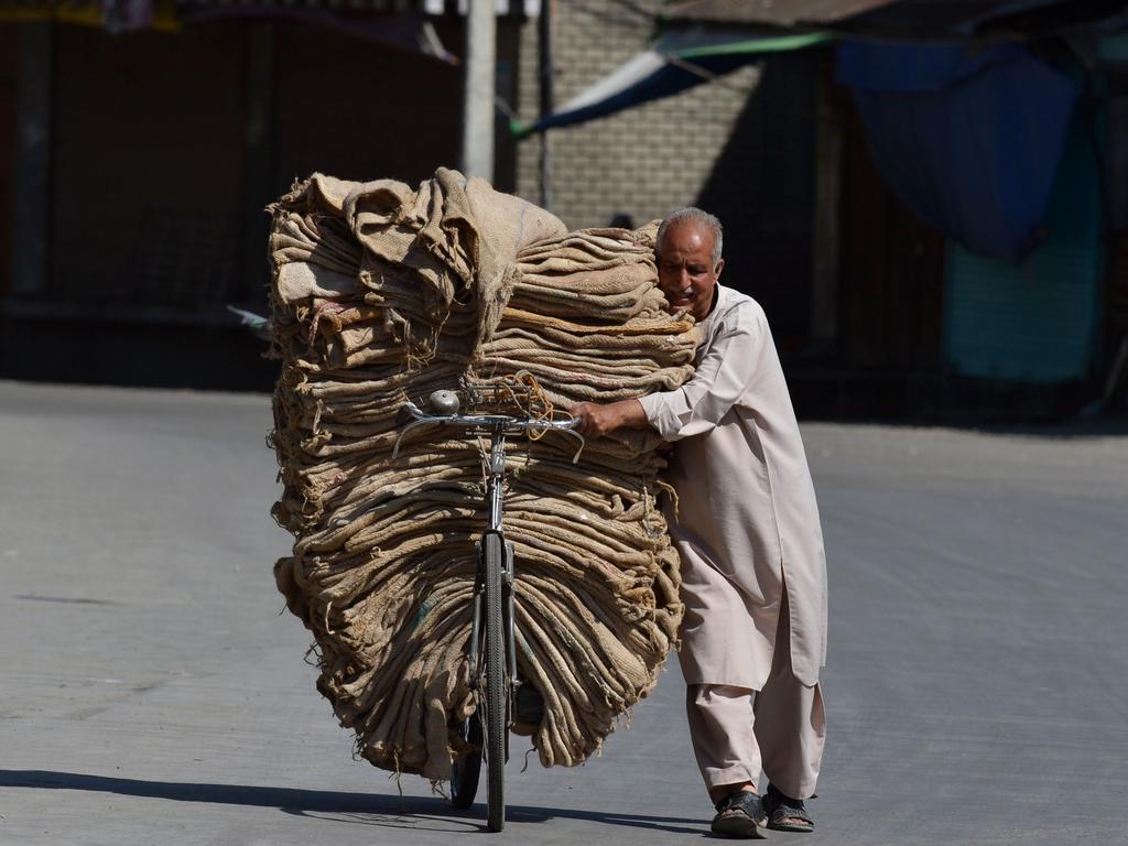 An Indian Kashmiri man carries sacks on his bicycle on the 13th day of a curfew in Srinagar on July 21, 2016. Residents in Indian-administered Kashmir are facing a shortage of food and critical medical supplies as the restive region continues to be under a security lockdown. / AFP PHOTO / TAUSEEF MUSTAFA