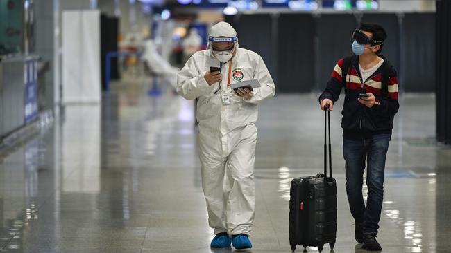 A member of airport security walks beside a passenger at Shanghai Pudong International Airport. Picture: AFP