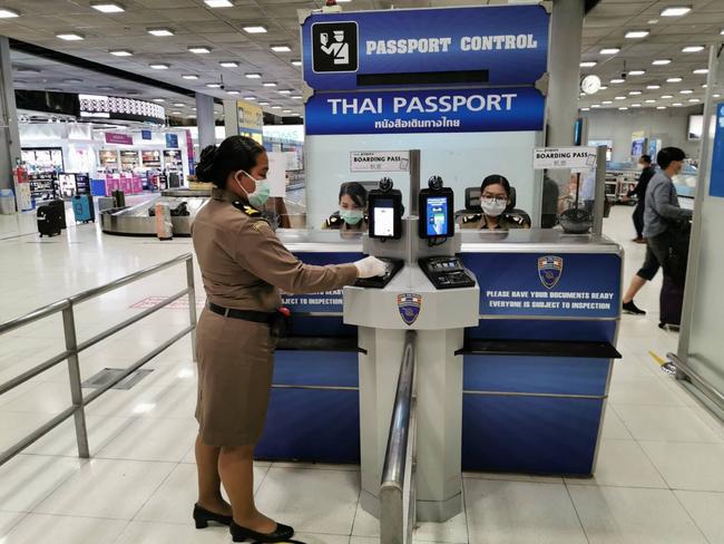 An immigration officer disinfecting the immigration booth and biometric device at Suvarnabhumi airport in Bangkok. Picture: AFP