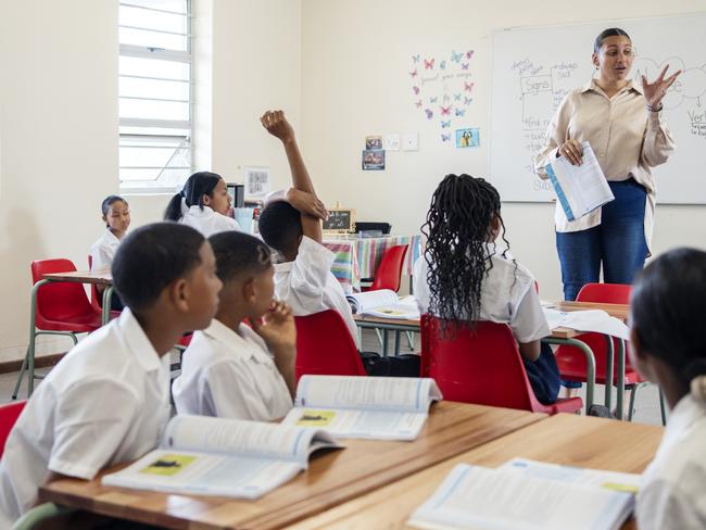 Schools of excellence: Female teacher teaching students during lecture in classroom at school.