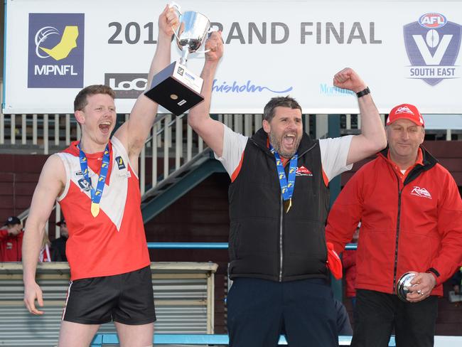 Red Hill captain Marcus Dal Lago and coach Jamie Mollo lift the premiership cup, alongsie club great Owie Shaw. Picture: Chris Eastman