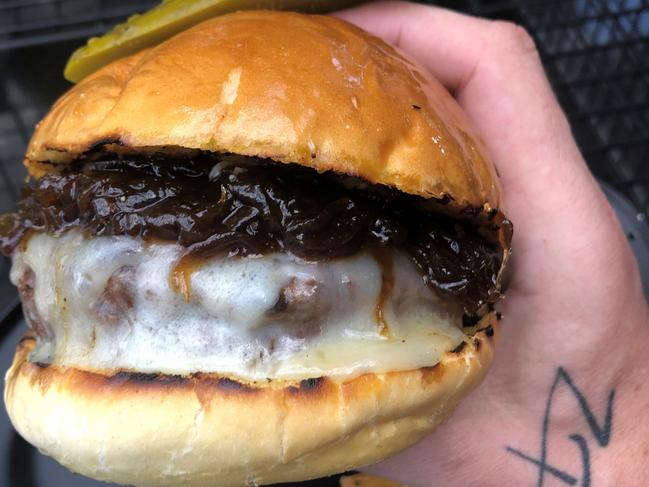 Ze Pickle's zEPICkle burger features 45-day dry age beef rib eye patty, provolone cheese, house onion jam on a garlic buttered pretzel bun.