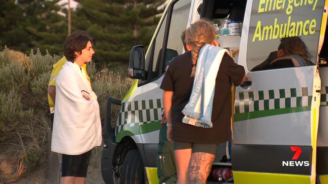 The teenage girl chats to ambulance officers after being rescued by two brothers while swimming off Moana Beach. Picture: 7NEWS