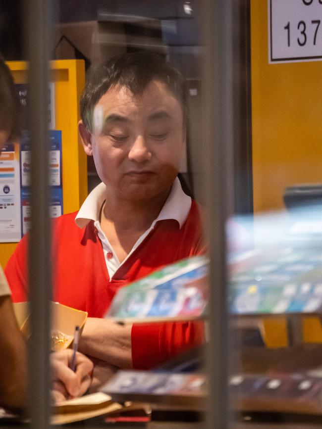 Wang watches on as police raid his store. Picture: AAP IMAGE/Monique Harmer