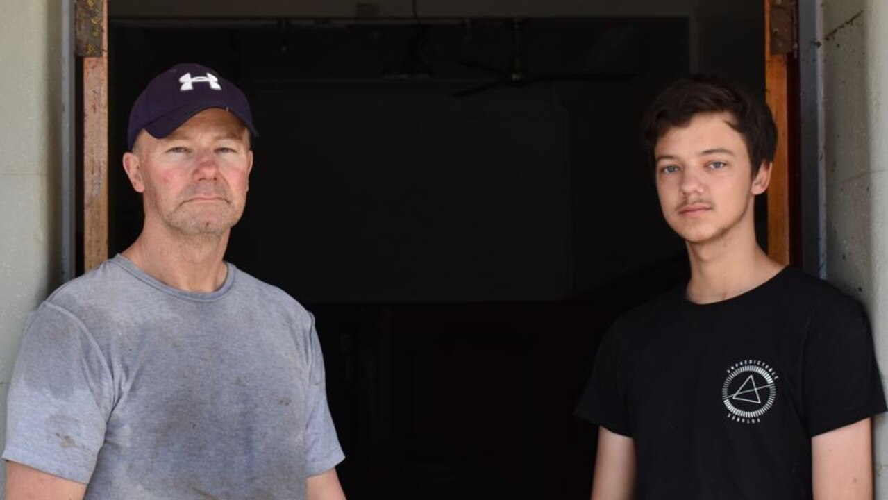 Empire Hotel owner Craig Mylrea (left) and his son, Zane Mylrea (right), were forced to sit in darkness while their downstairs pub went under in the February floods. The height of the water can be seen on the wall next to Zane’s head.