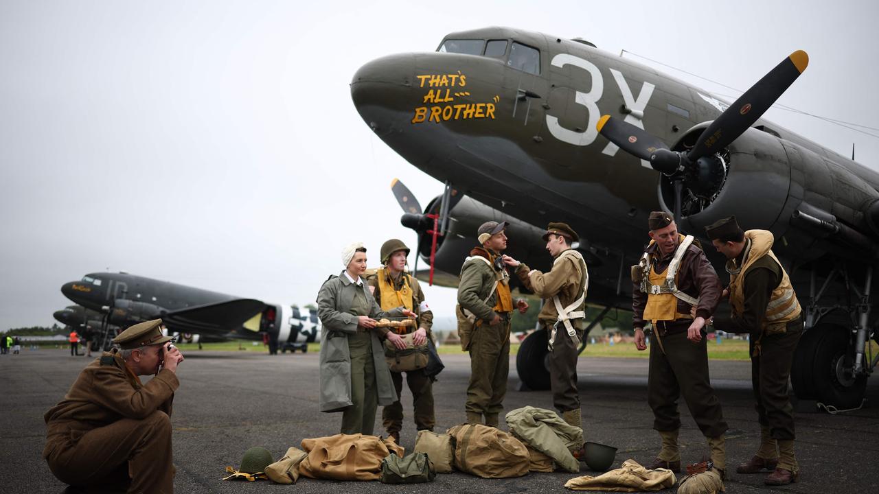 World War II reenactors pose for a photograph beside a C-47, an aircraft that carried paratroopers over the drop zones in Normandy, France. Picture: Henry Nicholls/AFP