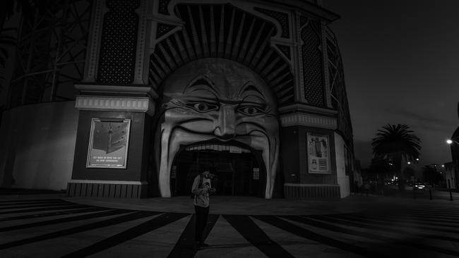 A lone man outside Melbourne’s deserted Luna Park as curfew approaches on September 10. Picture: Getty