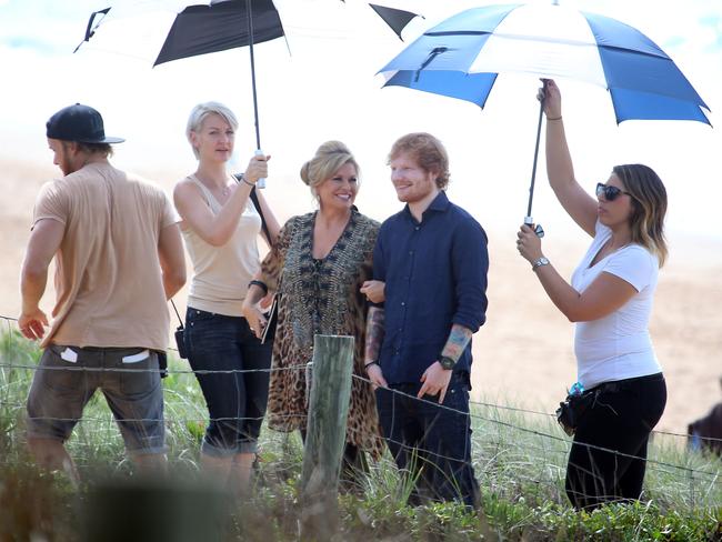 Umbrella-ella-ella: ... Ed Sheeran and actress Emily Symons, who plays Marilyn Chambers on Home and Away) get shady at Summer Bay. Picture: Andrew Murray