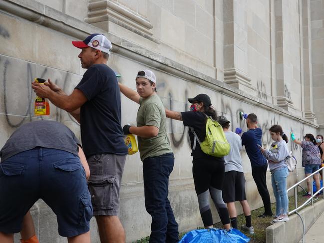 Kyle Rittenhouse, pictured in the green shirt facing the camera, cleans graffiti in Kenosha before allegedly shooting dead two Black Lives Matter protesters. Picture: Scott Olson/Getty