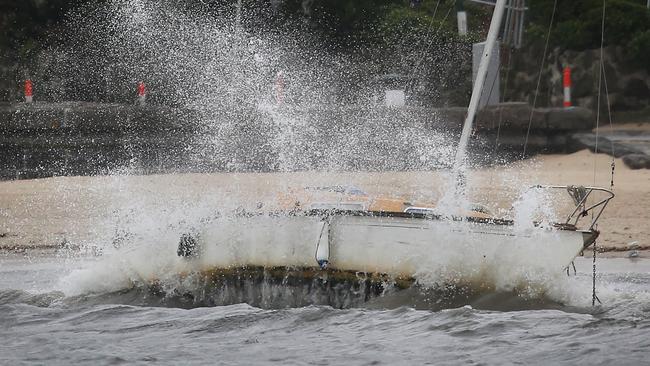 Waves smash a sailing boat on St Kilda Beach. Picture: David Caird