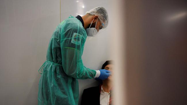 A health worker takes a swab from a passenger of a flight from China at the Covid-19 testing booths. Picture: AFP.