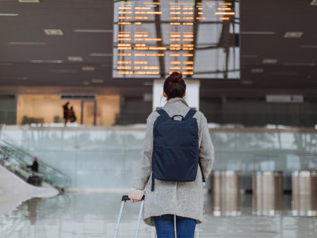 Woman at the airport, checking the flight schedule on the arrival departure board