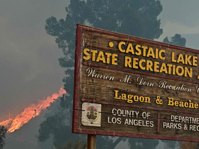 Flames race up the hill as the plume of smoke from the Hughes fire fills the sky. Picture: AFP