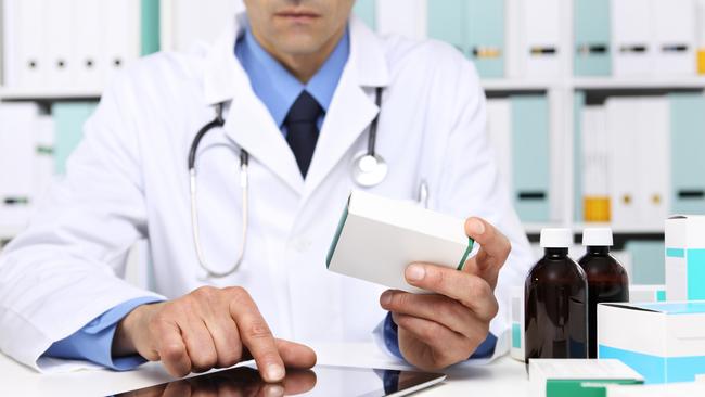 Doctor reading a Digital Tablet with drug boxes in hand at Office Desktop. Health care, Medical and Pharmacy Concept.