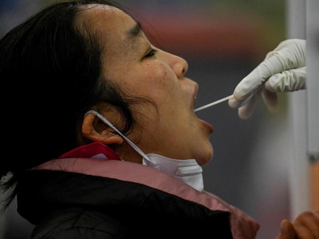 A woman has a swab sample taken to be tested for the Covid-19 coronavirus at a collection station in Beijing on November 20, 2022. (Photo by Noel CELIS / AFP)