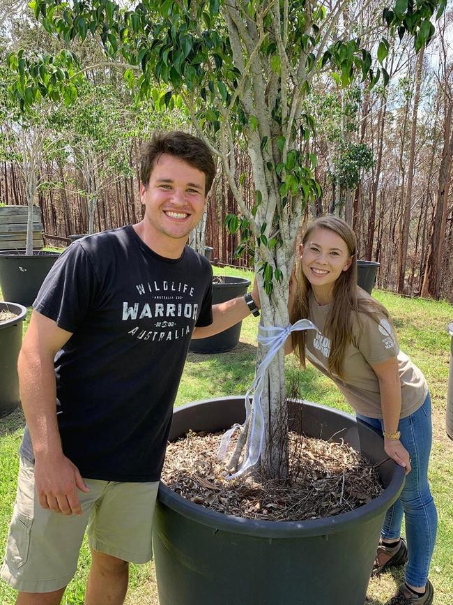 Bindi Irwin and Chandler Powell pose with a tree gifted to them by Russell Crowe for their wedding in 2020.