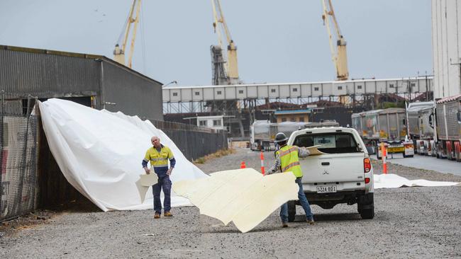 Workers collect debris from the remains of a giant inflatable storage silo at Hallet Group in Port Adelaide, after it collapsed in high winds. Picture: NCA NewsWire / Brenton Edwards