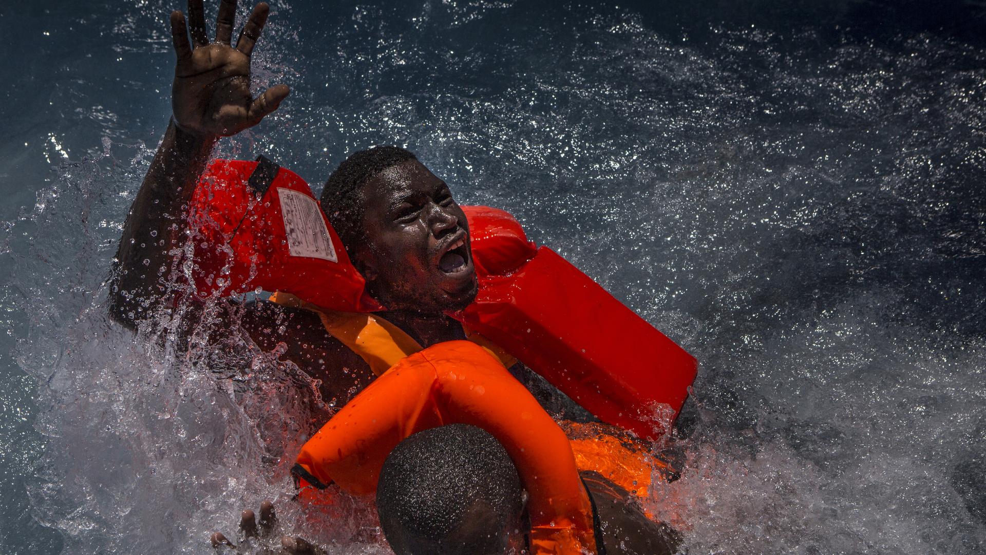 In this image released Monday Feb. 13, 2017, by World Press Photo titled "Mediterranean Migration" by photographer Mathieu Willcocks, which won third prize in the Spot News, Stories, category of the World Press Photo contest shows two men panicking and struggling in the water during their rescue. Their rubber boat was in distress and deflating quickly on one side, tipping many migrants in the water. They were quickly reached by rescue swimmers and brought to safety. (Mathieu Willcocks, World Press Photo via AP)