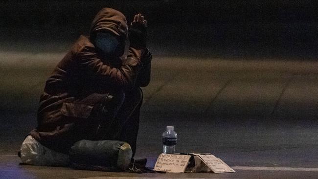 Homeless person wearing a mask begs for spare change. Picture: Jason Edwards