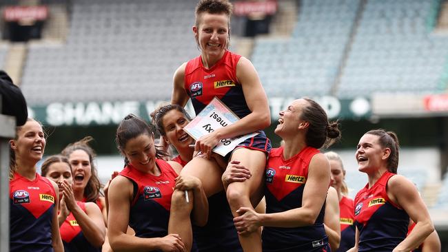 Melbourne players lchair Karen Paxman off after her 50th game in their preliminary final win.