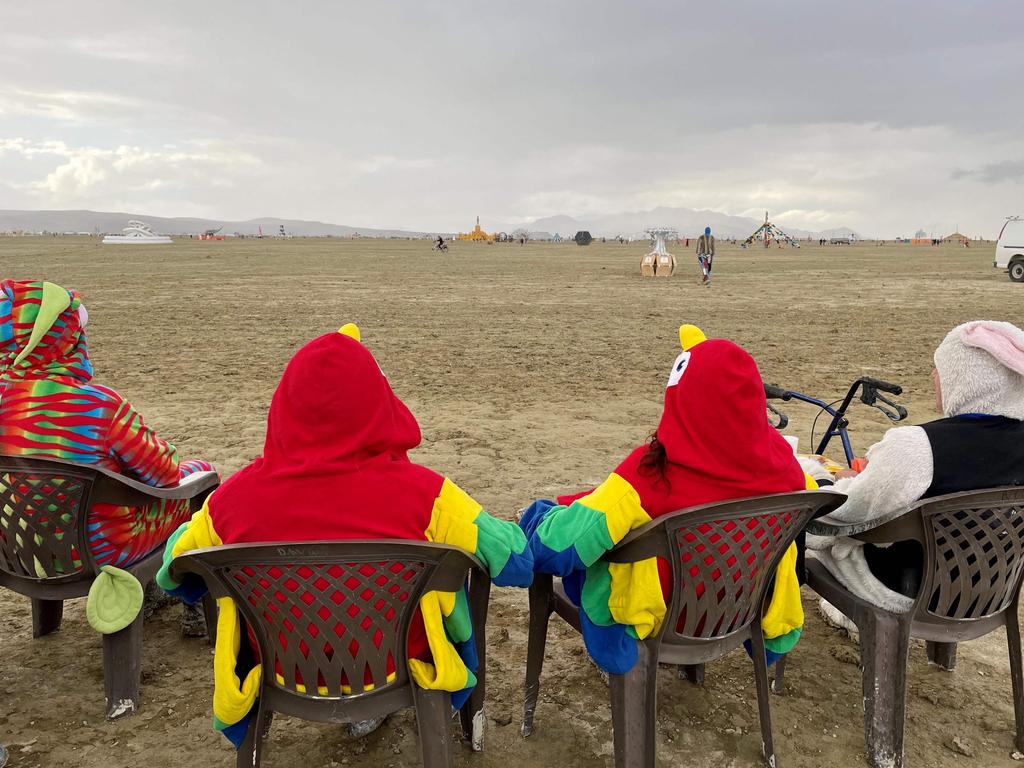 Attendees sit on a muddy desert plain after heavy rains turned the annual Burning Man festival site into a mud pit. Picture: AFP