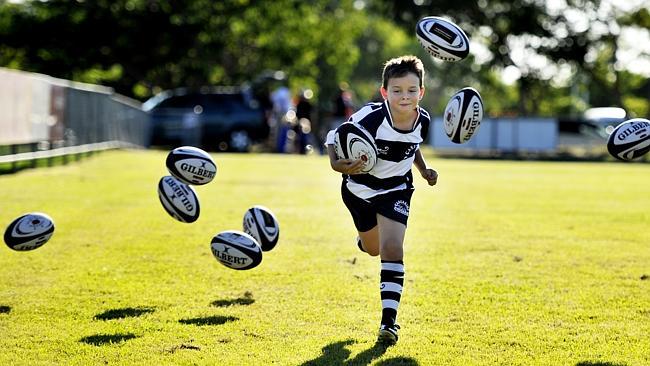 Riley Lewis, 8, testing out new junior rugby union balls presented to his club Casuarina 